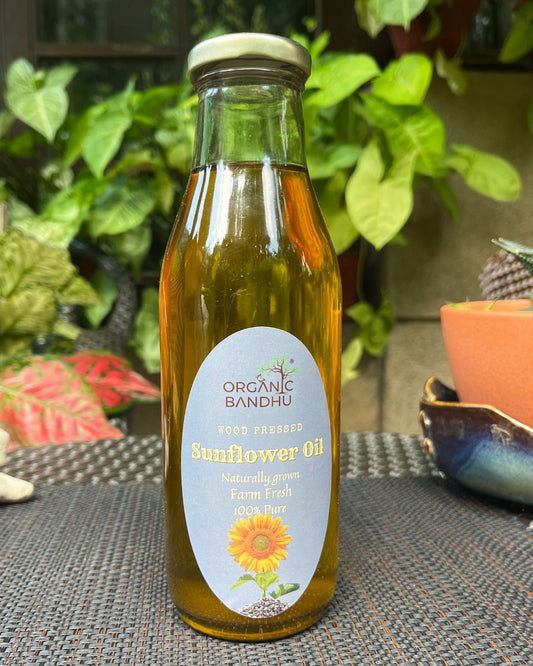 Bottle of Organic Bandhu sunflower oil on a table with plants in the background
